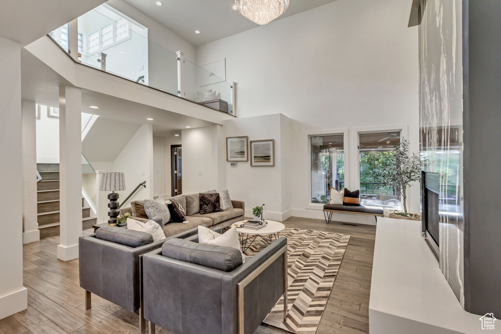 Living room featuring a high ceiling, wood-type flooring, and an inviting chandelier