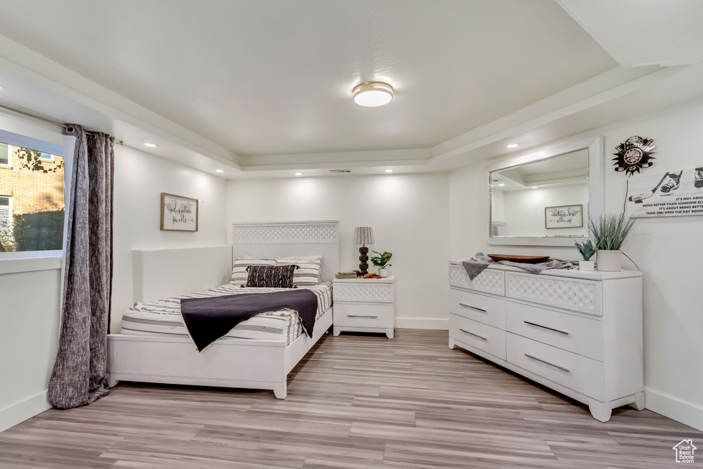 Bedroom with light hardwood / wood-style floors and a tray ceiling