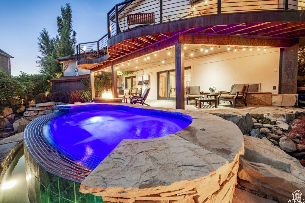 Pool at dusk with a hot tub and a patio