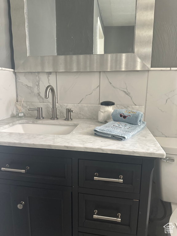 Bathroom featuring toilet, backsplash, and vanity