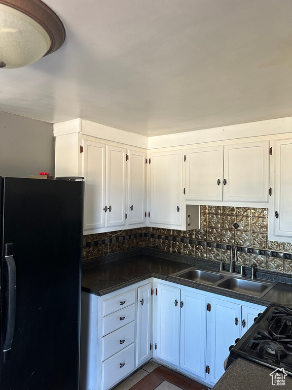Kitchen with white cabinetry, black appliances, sink, and decorative backsplash