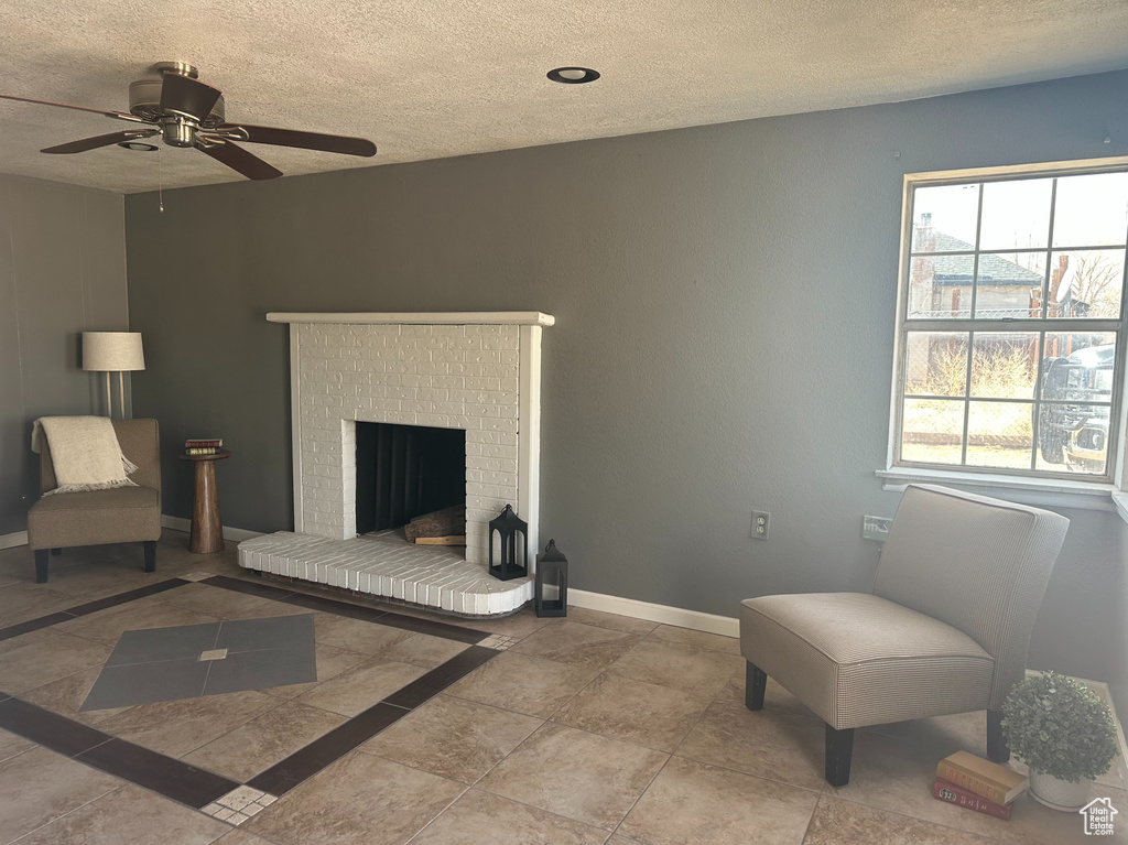 Sitting room featuring a ceiling fan, a fireplace, baseboards, and a textured ceiling