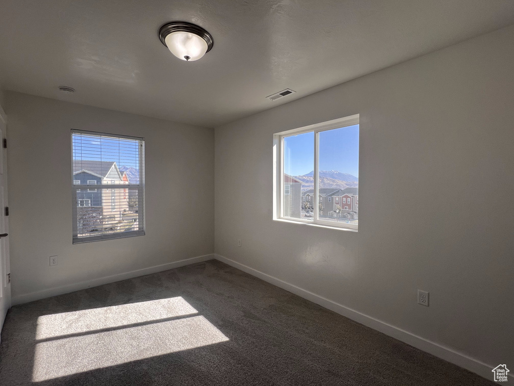 Carpeted empty room with a mountain view and a healthy amount of sunlight