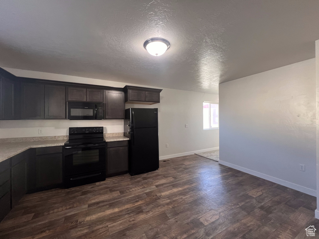 Kitchen featuring a textured ceiling, dark brown cabinetry, black appliances, and dark hardwood / wood-style flooring