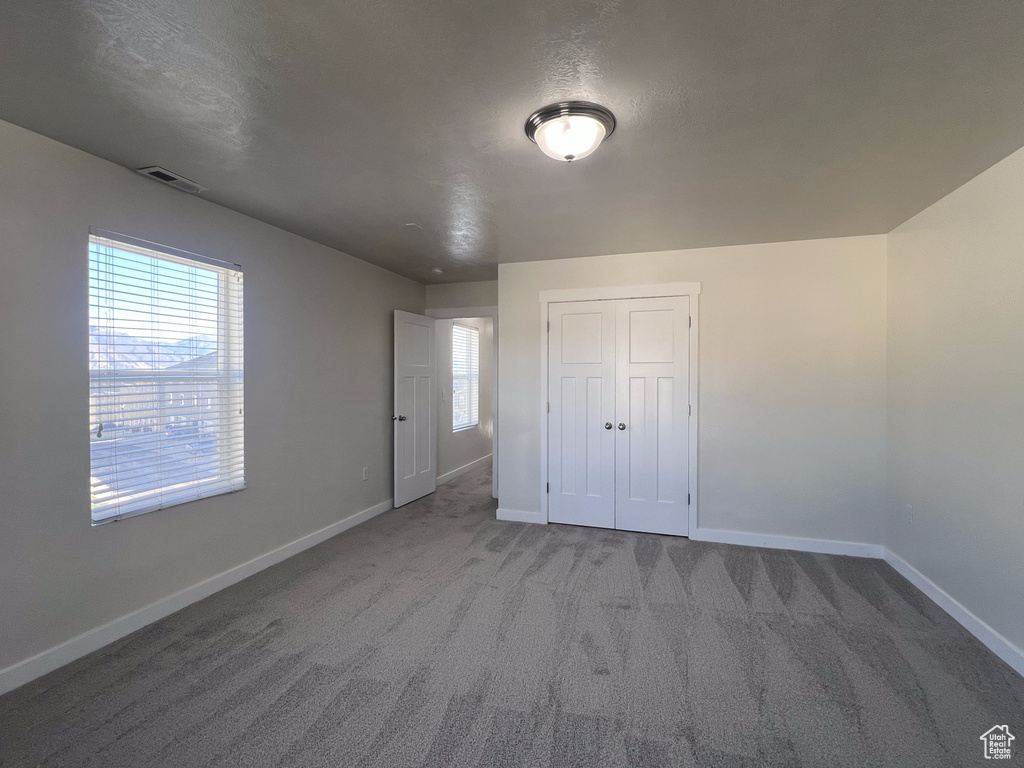 Unfurnished bedroom with a closet, a textured ceiling, and carpet