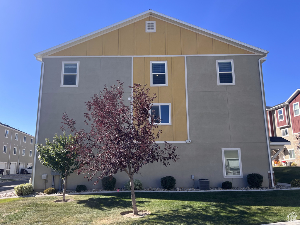 View of side of home featuring central AC and a yard