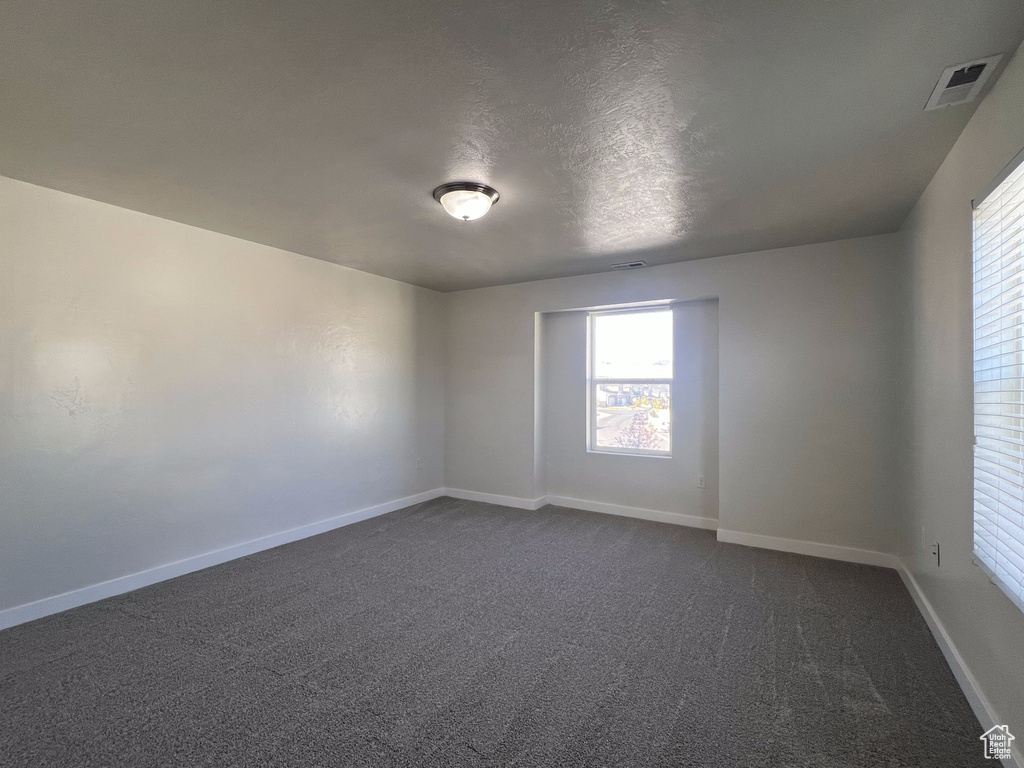 Spare room featuring a textured ceiling and dark carpet