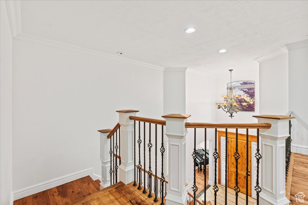 Stairs featuring ornamental molding, an inviting chandelier, and hardwood / wood-style floors