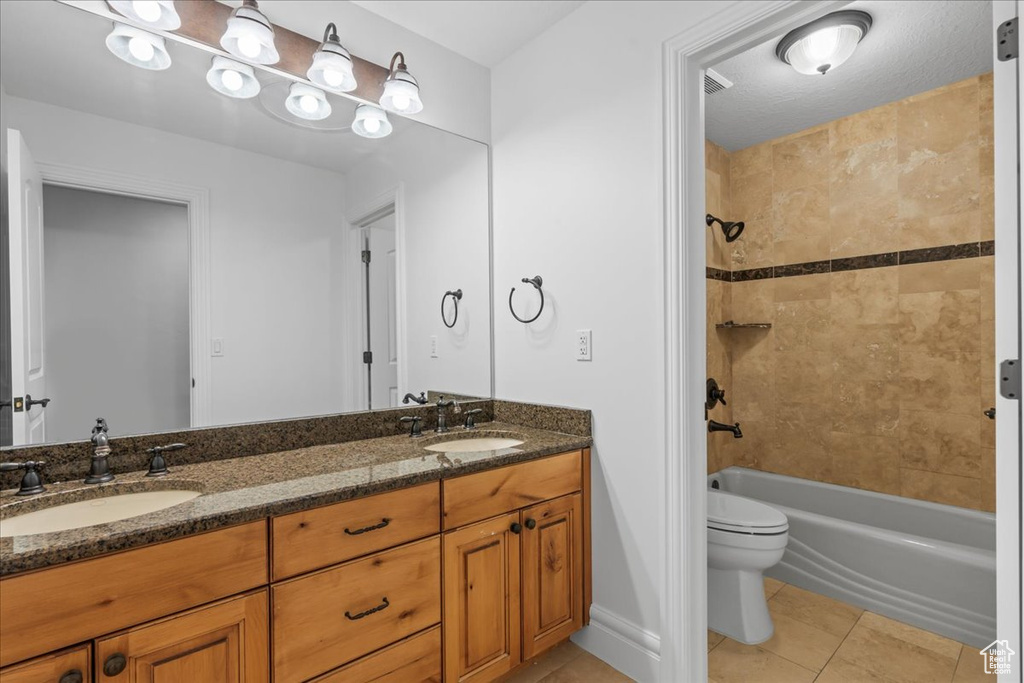 Full bathroom with vanity, toilet, tile patterned floors, and tiled shower / bath combo