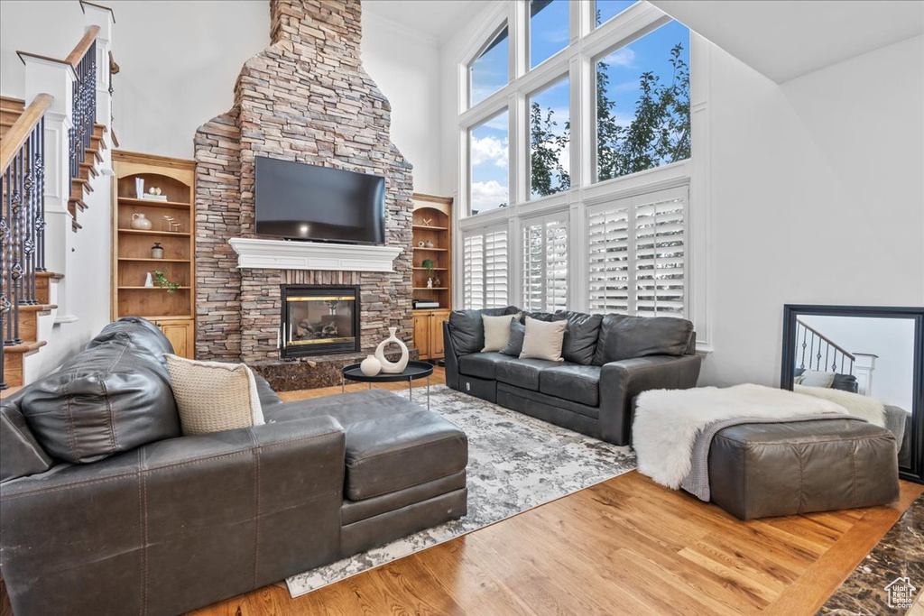 Living room featuring a fireplace, wood-type flooring, and a high ceiling