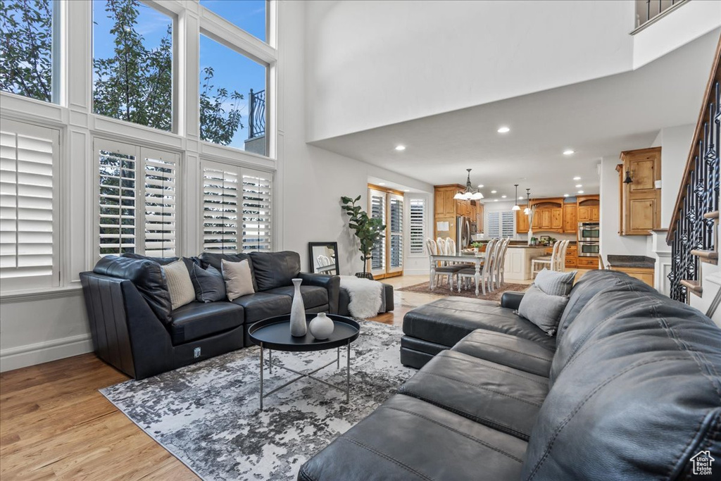 Living room featuring a towering ceiling, an inviting chandelier, and light wood-type flooring