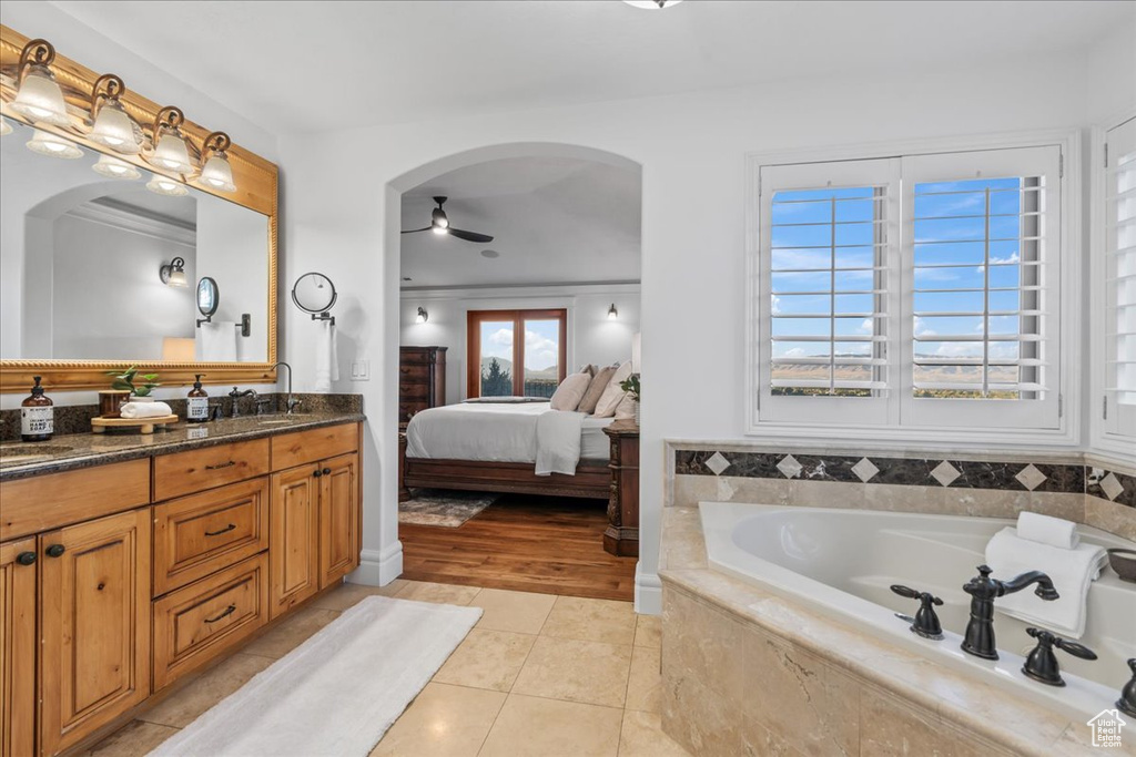 Bathroom featuring tile patterned floors, crown molding, a relaxing tiled tub, vanity, and ceiling fan