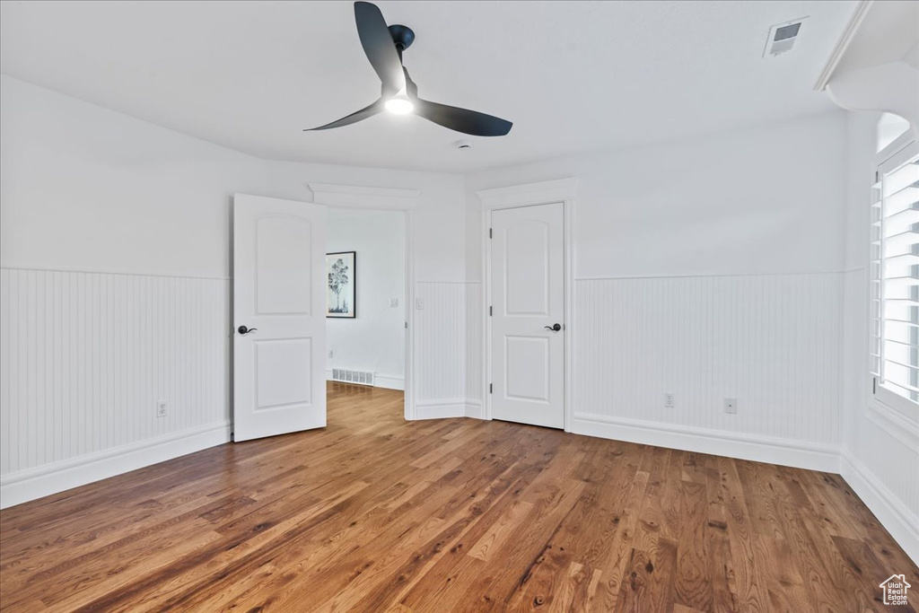 Unfurnished bedroom featuring ceiling fan, wooden walls, and hardwood / wood-style floors