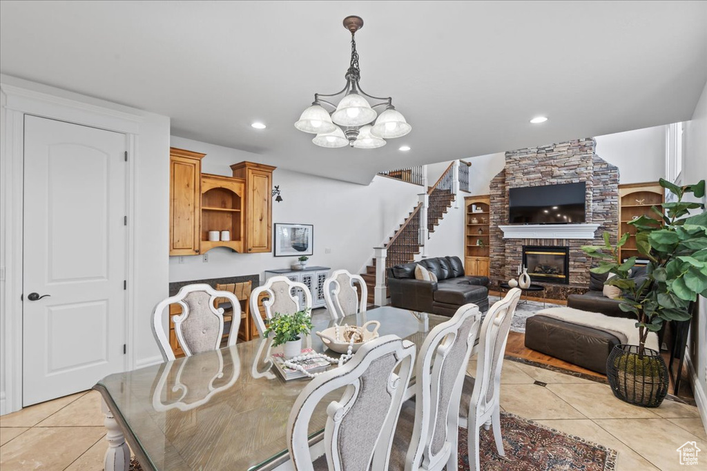 Dining room with a chandelier, a fireplace, and light tile patterned floors