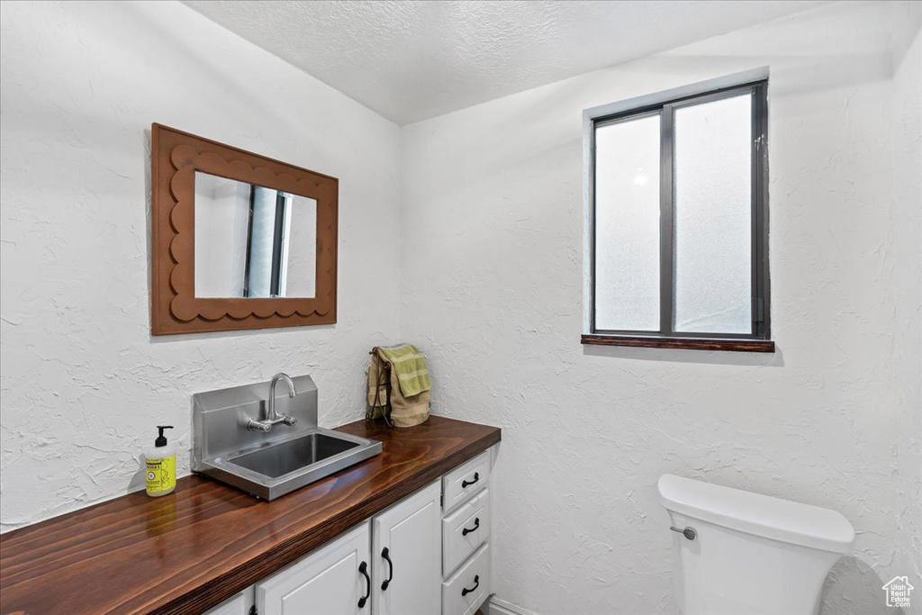 Bathroom with vanity, toilet, and a textured ceiling