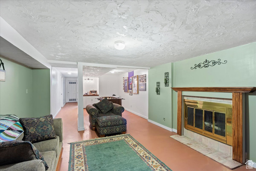 Living room featuring a textured ceiling, a tiled fireplace, and concrete flooring