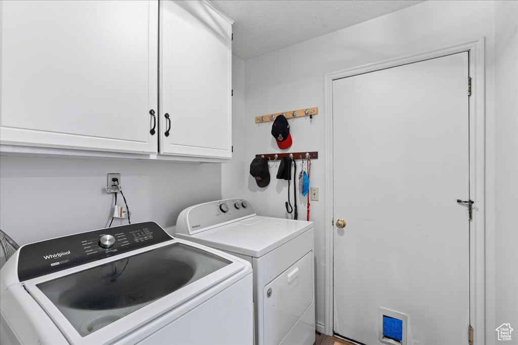 Laundry room featuring cabinets, a textured ceiling, and washing machine and clothes dryer