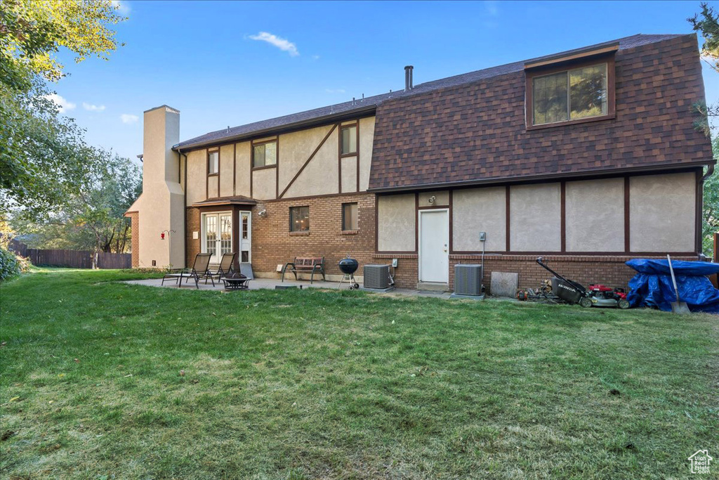 Rear view of house featuring a patio, central air condition unit, and a lawn