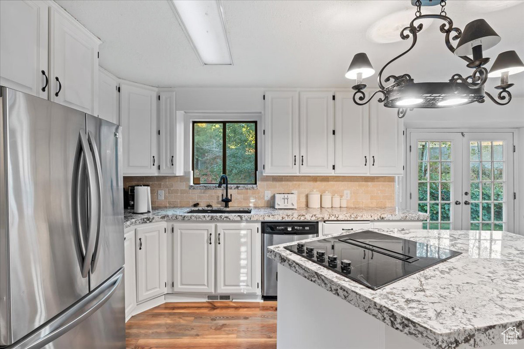 Kitchen featuring white cabinets, backsplash, light wood-type flooring, sink, and stainless steel appliances