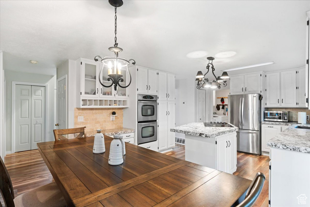 Dining room with dark wood-type flooring and an inviting chandelier