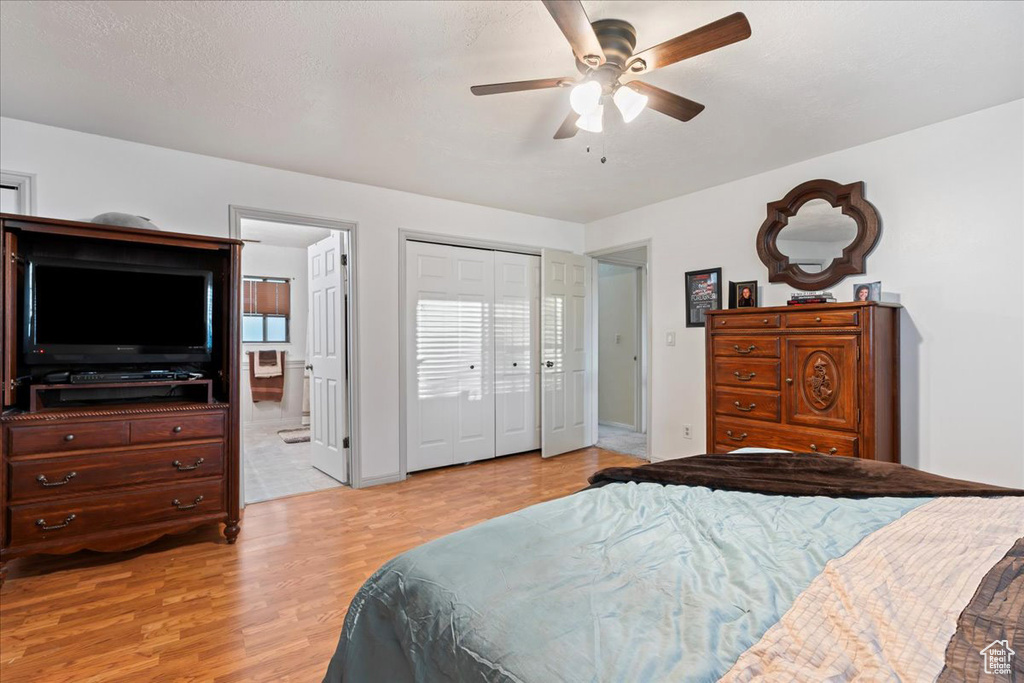 Bedroom featuring a closet, ensuite bathroom, light wood-type flooring, and ceiling fan