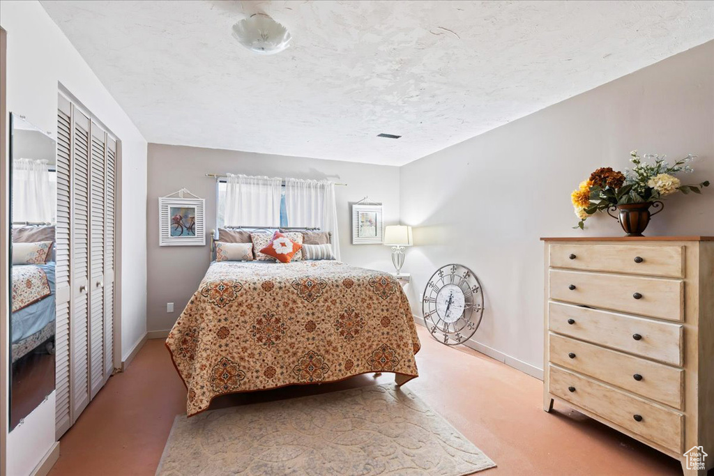 Bedroom featuring a closet, a textured ceiling, and light colored carpet