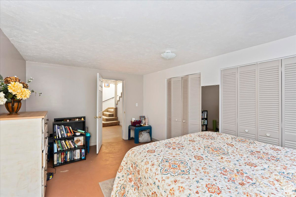 Bedroom with two closets, a textured ceiling, and light colored carpet