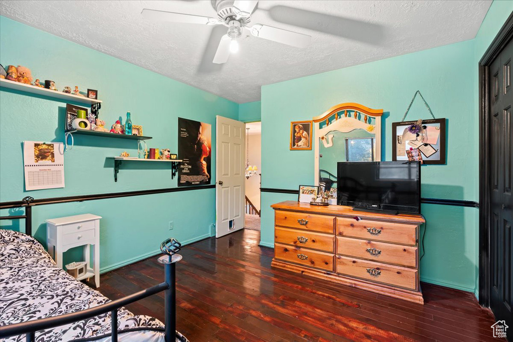 Bedroom with ceiling fan, a textured ceiling, and dark hardwood / wood-style flooring