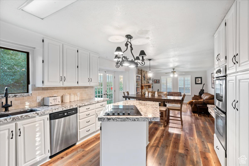 Kitchen with white cabinetry, a center island, a wealth of natural light, and stainless steel appliances