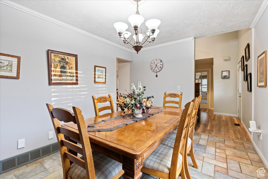 Dining space with crown molding, light hardwood / wood-style flooring, a textured ceiling, and a chandelier