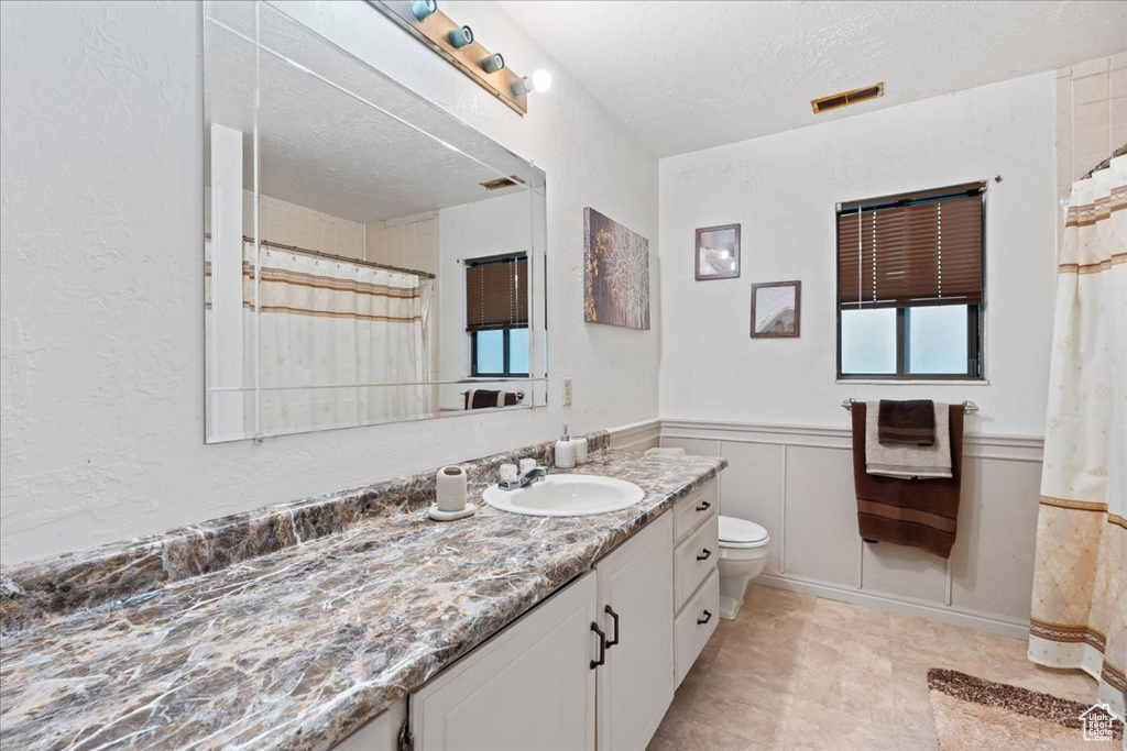 Bathroom featuring toilet, a textured ceiling, and vanity