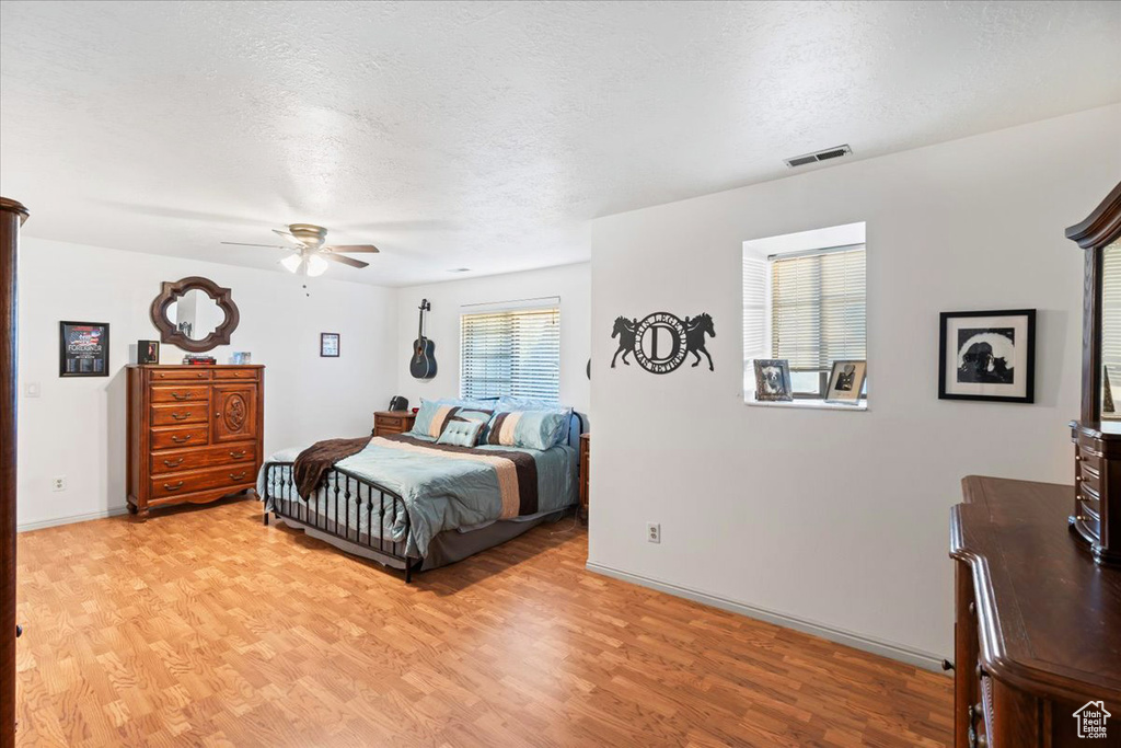 Bedroom featuring ceiling fan, a textured ceiling, and light wood-type flooring