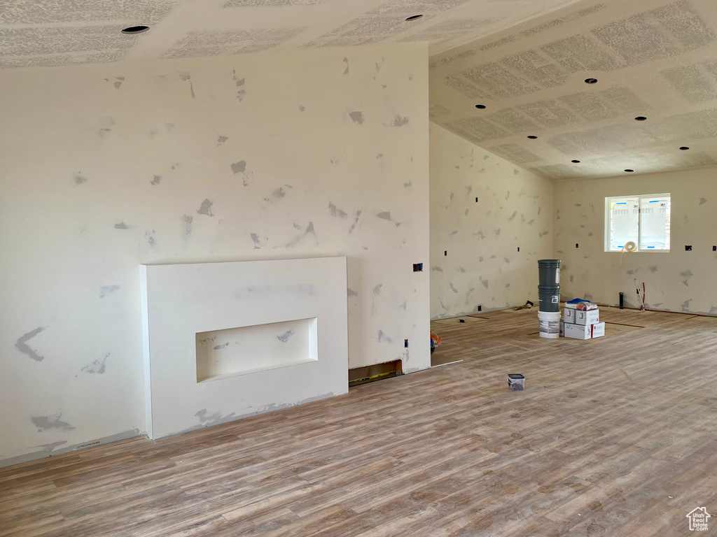 Unfurnished living room featuring lofted ceiling and hardwood / wood-style floors