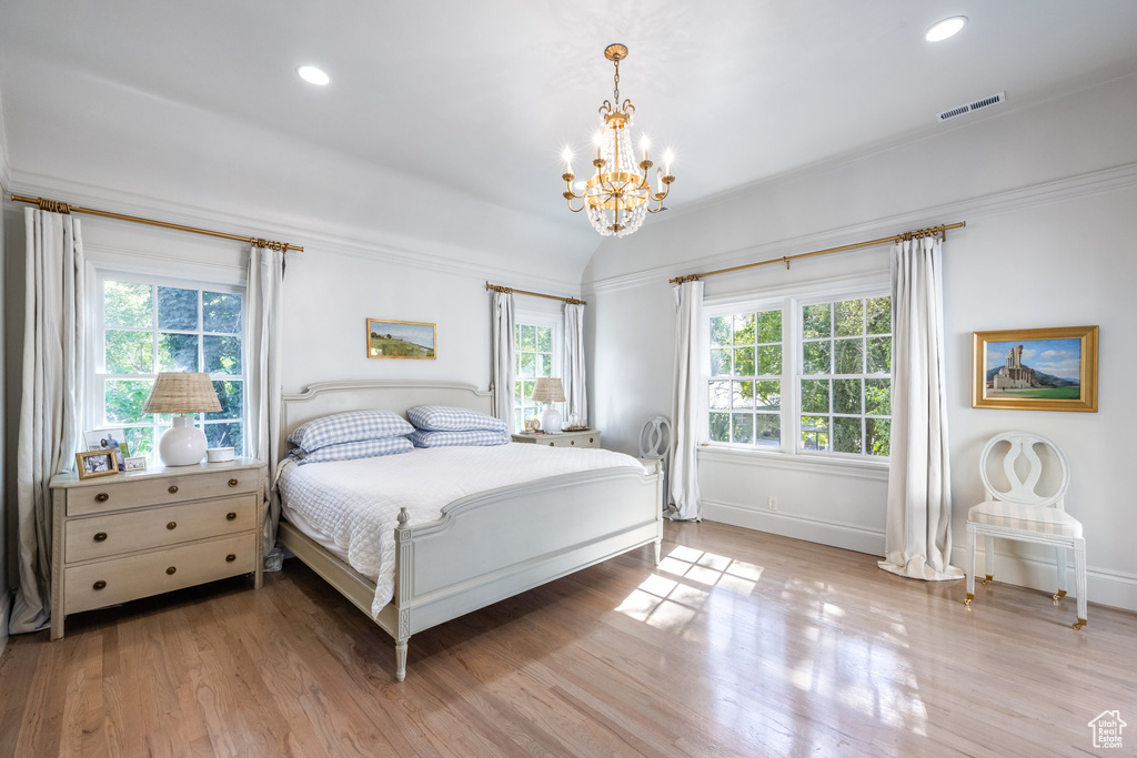 Bedroom with light hardwood / wood-style flooring, ornamental molding, and a notable chandelier