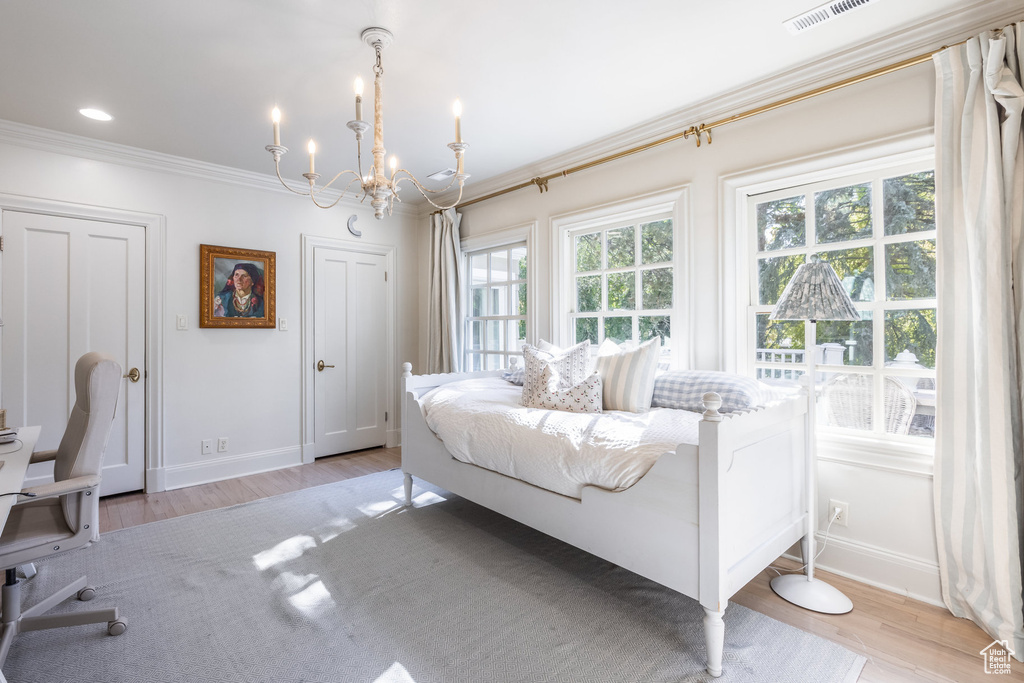 Bedroom with crown molding, a notable chandelier, and light wood-type flooring