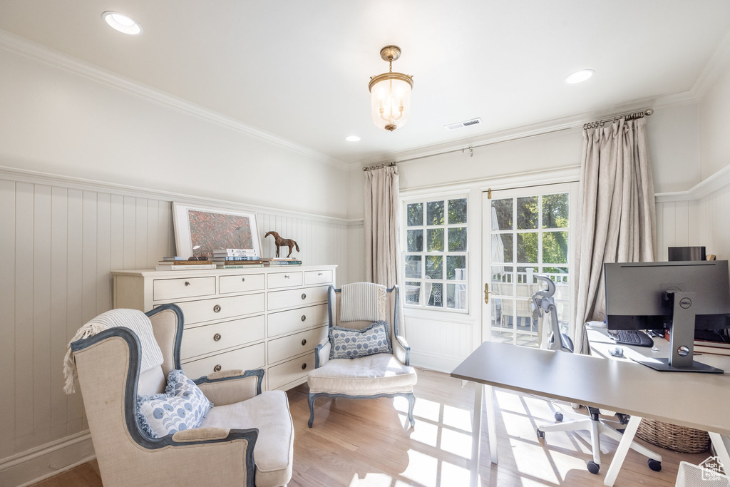 Home office with a chandelier, crown molding, light hardwood / wood-style floors, and wooden walls