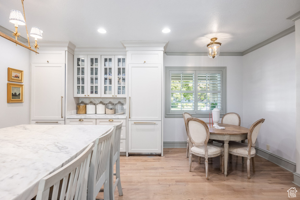 Dining space featuring an inviting chandelier, ornamental molding, and light wood-type flooring