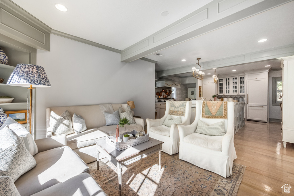 Living room with crown molding, hardwood / wood-style flooring, beamed ceiling, and a chandelier