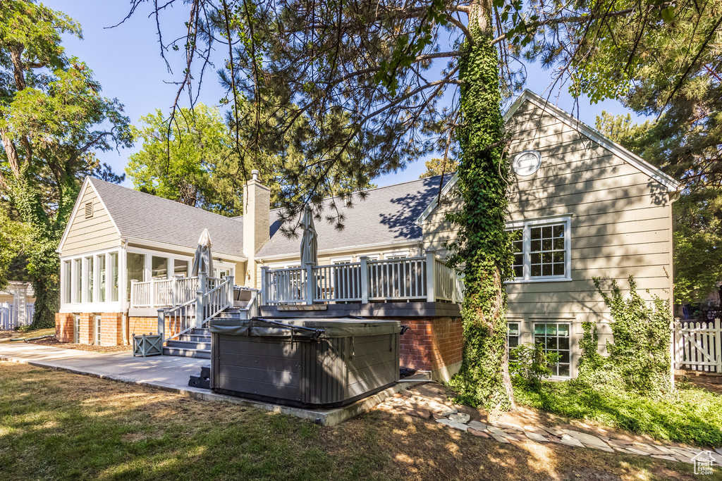 Rear view of property featuring a hot tub and a deck