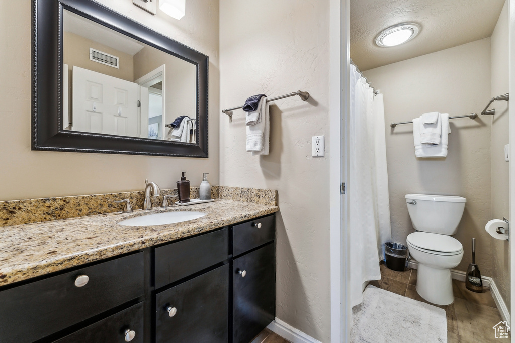 Bathroom with vanity, toilet, baseboards, and visible vents