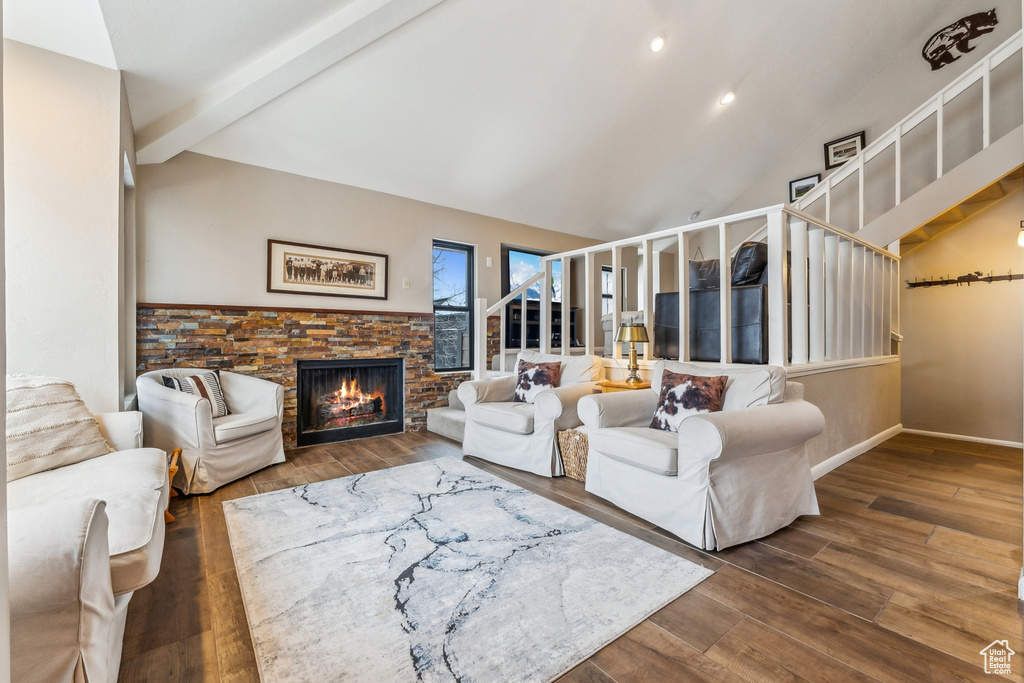 Living room featuring vaulted ceiling with beams, wood finished floors, recessed lighting, and a lit fireplace