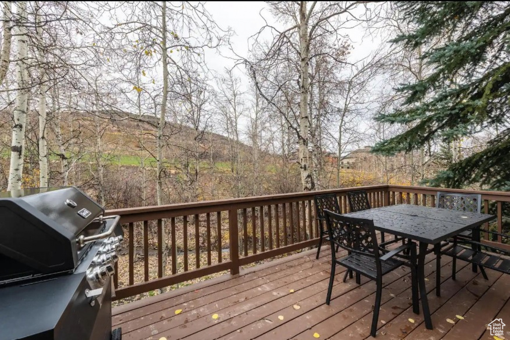 Wooden deck featuring outdoor dining area and a grill