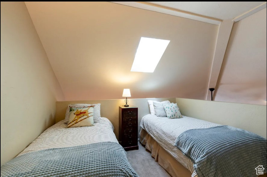 Carpeted bedroom with lofted ceiling with skylight