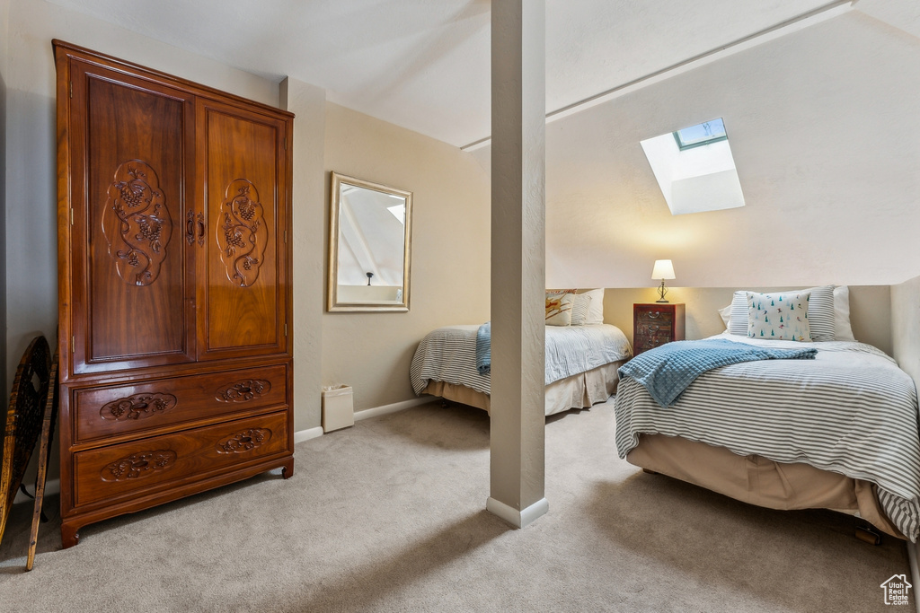 Bedroom featuring a skylight, baseboards, and light carpet