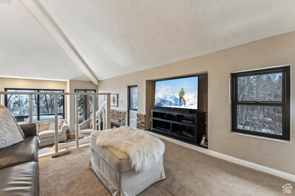 Living area featuring baseboards, lofted ceiling with beams, carpet, and a textured wall