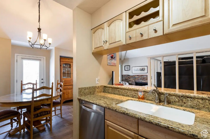 Kitchen with light brown cabinetry, sink, light stone countertops, dishwasher, and dark hardwood / wood-style floors