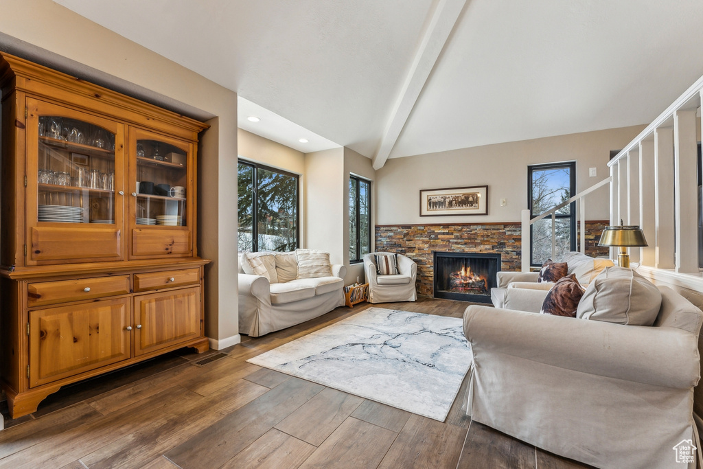 Living room featuring lofted ceiling with beams, recessed lighting, a fireplace, dark wood-style flooring, and stairs