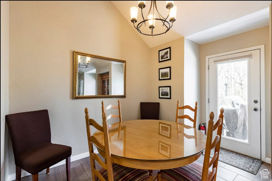 Dining area featuring wood-type flooring, vaulted ceiling, and an inviting chandelier