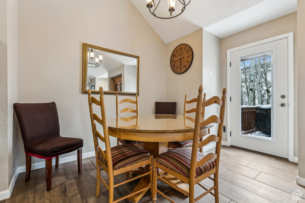 Dining room featuring a chandelier, baseboards, lofted ceiling, and wood finished floors