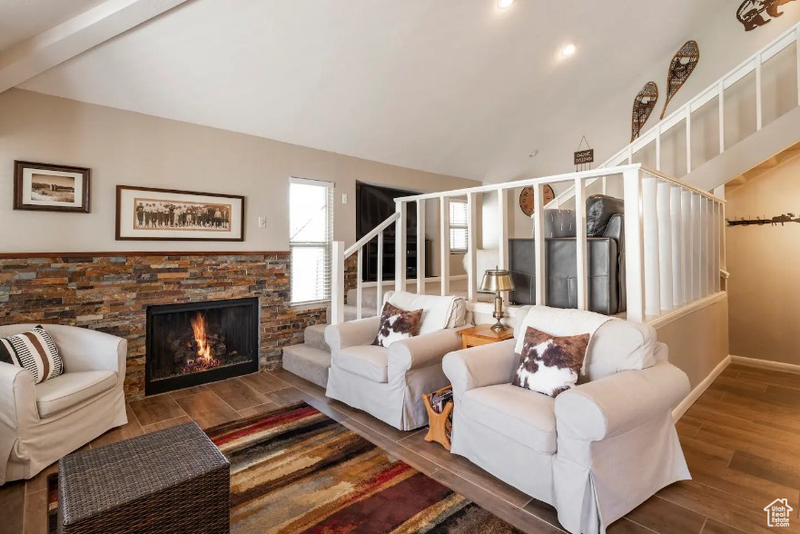 Living room with lofted ceiling with beams, wood-type flooring, and a fireplace